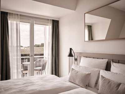 Doppelbett mit Blick auf den Balkon im Schlafzimmer des Family Apartments.