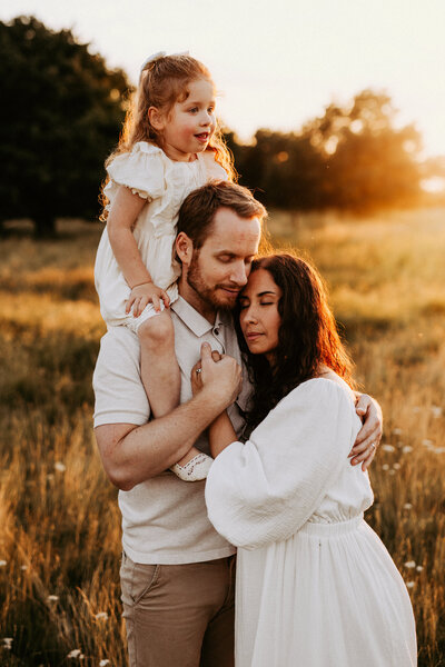 en familj står och håller om varandra i solnedgången på ett fält under deras familjefotografering i göteborg