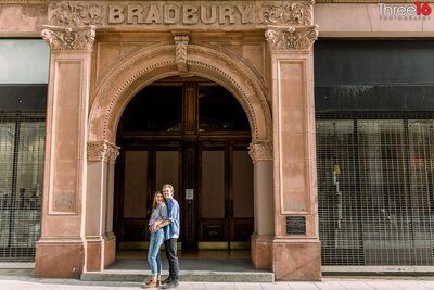 Groom to be holds his Bride from behind during a photoshoot in front of the Bradbury Building