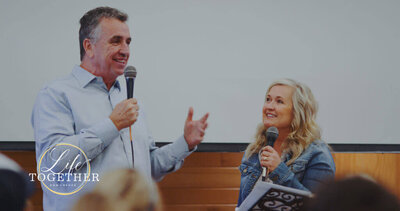 Dr. Don Worcester at a speaking engagement with microphone in hand 