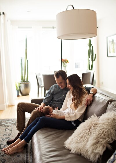 mom and dad sitting on their couch with their rband new baby boy during their denver photos