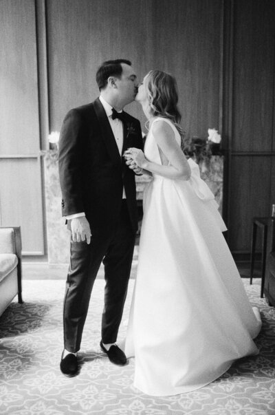 Black and white photo of a bride and groom sharing a kiss.