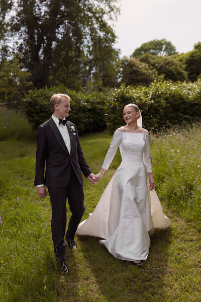 Wedding photographer captures couple taking a stroll hand in hand at their french chateau wedding.