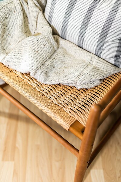 Bohemian woven basket accent chair with striped pillow and knitted blanket in Carlsbad, California.