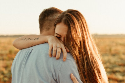 Girl getting emotional as she hugs her fiance at engagement session at sunrise