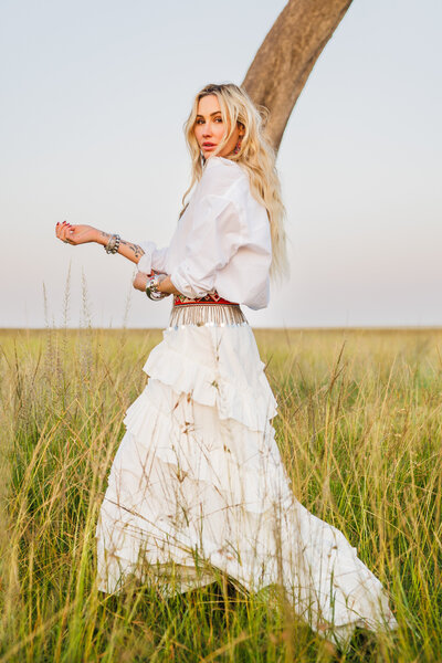 Alexis, founder of House of Imara, standing in a flowing white dress in the African grasslands.