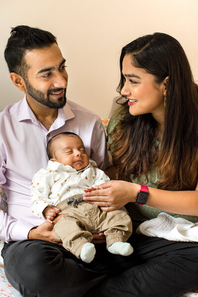 Family photo in Boone, NC of a mom and dad smiling at their infant son during a newborn family session.