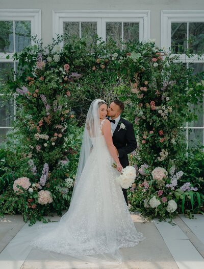 Bride and Groom in front of floral wall