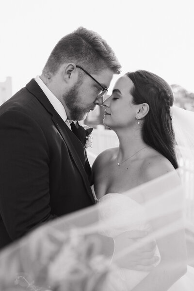 close-up black and white photo of bride and groom nose to nose 