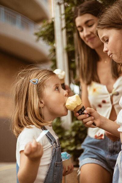 image of big sister letting young sister lick her ice cream.