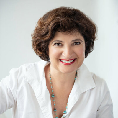 French woman in a red lip and and black lined eyes and mascara with lashes in a white shirt