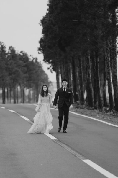 a Singaporean couple walk on an empty road in Jeju during their prewedding shoot