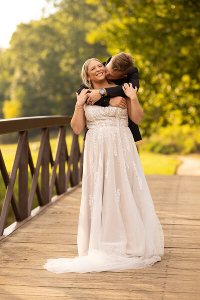 A groom and a bride share a kiss and embrace on their wedding day during a golden hour sunset at Valley of the Eagles. Photographed by Aaron Aldhizer