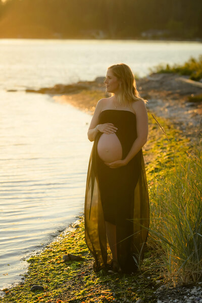 The golden glow of a backlit maternity photo session is captured by E. Benecki Photography as this momma to be wore a flowing black dress that beautifully highlight her baby bump.