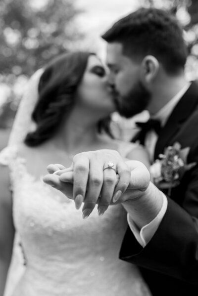 Witness the timelessness of love as the bride and groom exchange rings in this captivating black and white wedding photograph. An enduring symbol of their commitment.