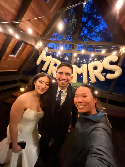 Smiling couple with their elopement photographer in a cabin with balloon strung Mr and Mrs
