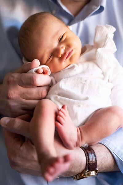 Newborn girl in white knit outfit while facing camera