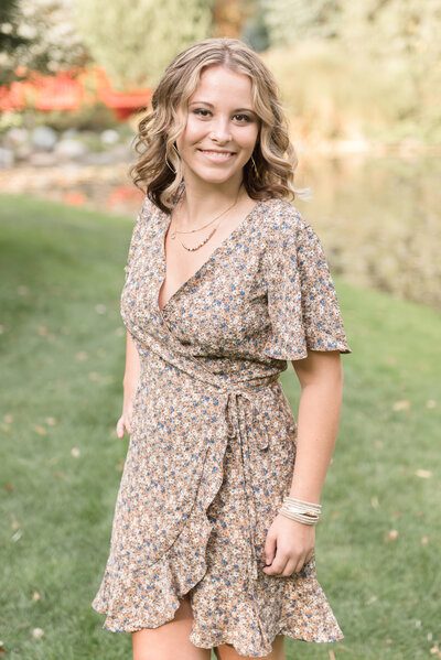 senior standing at Dow Gardens with one hand on hip looking at camera
