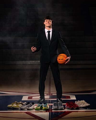 Senior Boy in Suit Standing in front of a Variety of Shoes with Basketball