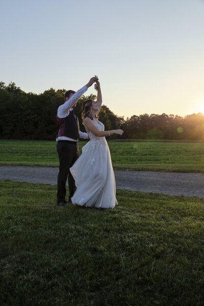 the couple dancing on the lawn of an outdoor venue at sunset.