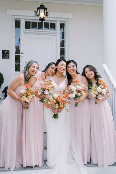 Bride posing with her bridesmaids in pink dresses with bright bouquets