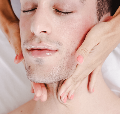 Hands giving a face lymphatic drainage massage to a man