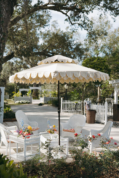 Bride and groom standing in front of the white ceremony arch at Uliana Estate in Lakeland, Florida, surrounded by floral arrangements and oak trees