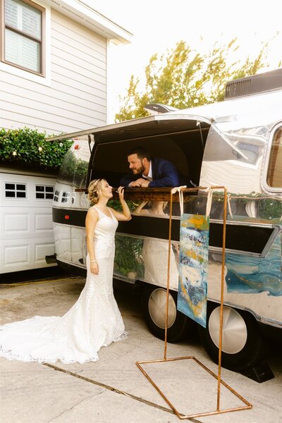 couple in an airstream with a hand acrylic sign on a copper stand