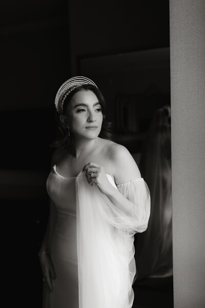 Bride standing by the window at Hotel LeVeque before her Franklin Park Conservatory wedding in Columbus, Ohio, photographed by Rainstorm Photo & Video in soft, natural light with elegant, editorial tones.