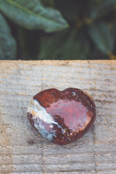 A red and gold ocean jasper heart-shaped crystal.