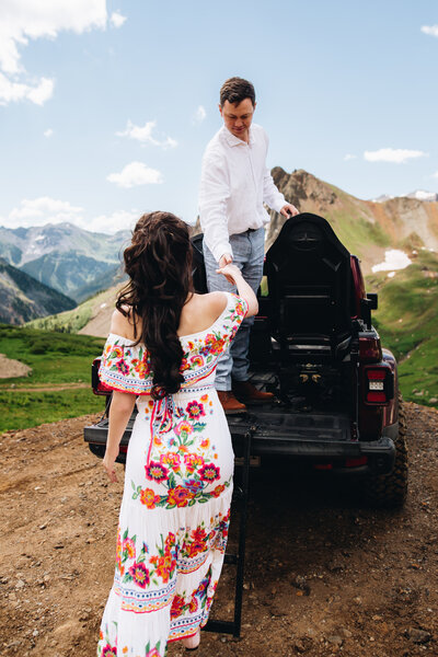 Groom helps bride into jeep during Ouray elopement.