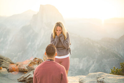 A surprised woman accepts her marriage proposal in front of Half Dome in Yosemite National Park