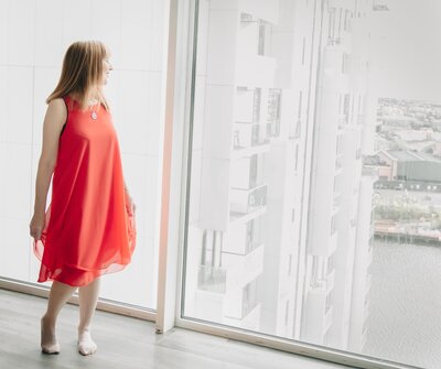 turning away towards a window in a red dress