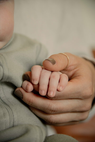 close up of woman holding a baby's hand