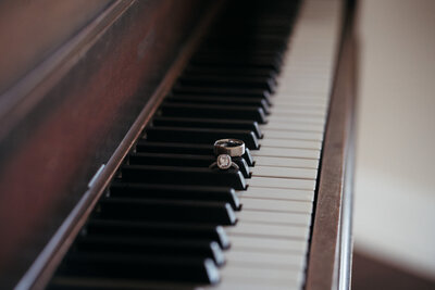 fine art image of wedding rings on piano in ballroom