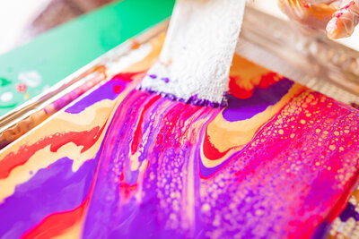 Paintbrush in colorful mixed paints for branding photoshoot with Tiffany McFalls.