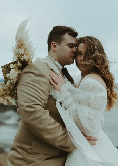 bride and groom hugging in front of dried florals