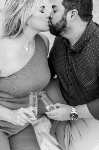 black and white photo of couple on beach engagement session with champagne