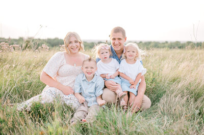 Family of 5 sitting in a field . Captured by Kristine Marie; light and airy Family Photography.