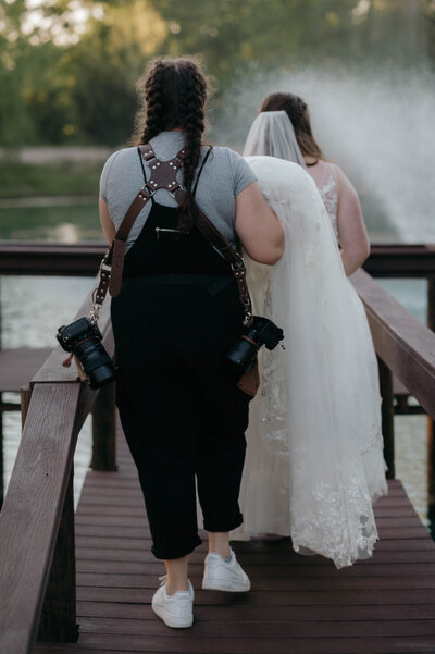 DFW Wedding Photographer Nicole Endress photography carrying bride's dress at wedding