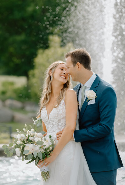 A bride and groom by a fountain at Castle Farms with their wedding photographer in Michigan