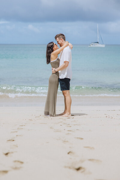 engaged couple kissing on beach