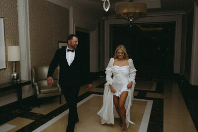 Bride and groom running through hotel halls