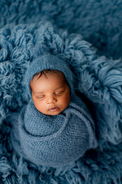 Newborn boy posed on blue backdrop