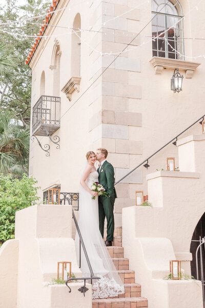 groom kissing bride on the steps of a wedding venue