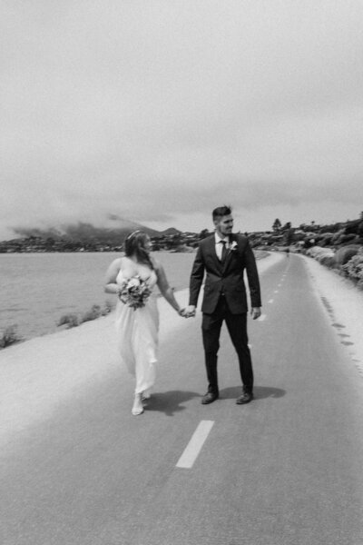bride and groom walking down the road next to the beach on their wedding day