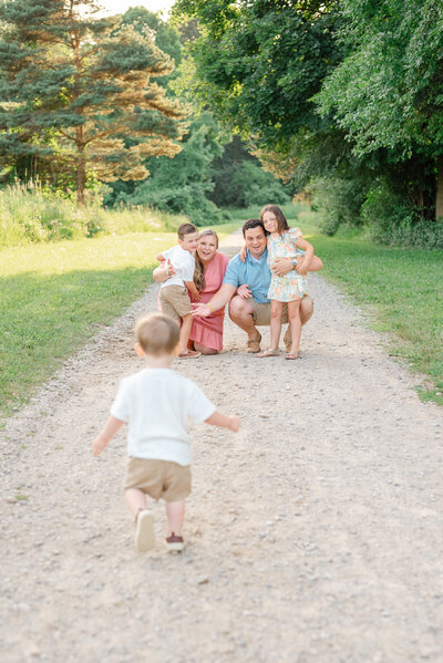 Toddler joyfully running towards his family, captured in motion outdoors.