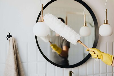 Person dusting a mirror during an airbnb cleaning