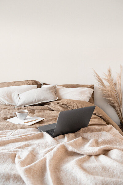Open laptop on bed next to coffee cup