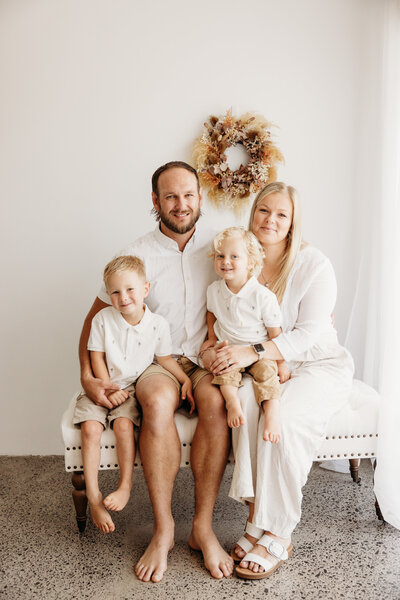 a family with two little boys posing for a portrait in the studio with auckland photographer michelle kelly